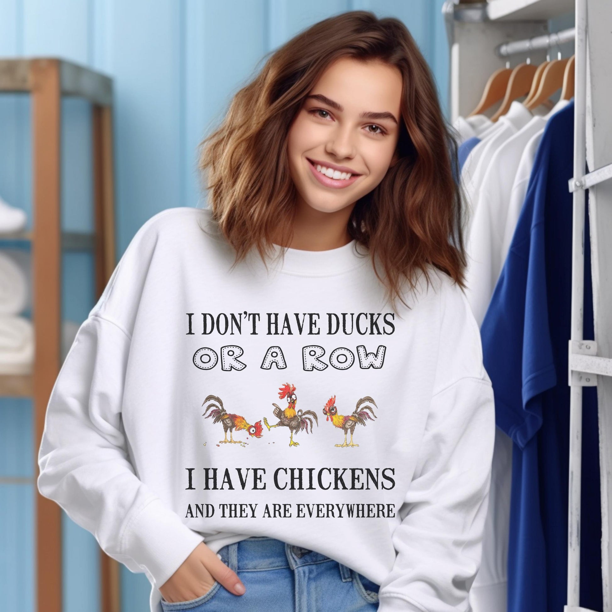 May include: White sweatshirt with the text "I DON'T HAVE DUCKS OR A ROW I HAVE CHICKENS AND THEY ARE EVERYWHERE." The graphic features three cartoon chickens in various poses. The sweatshirt is worn by a person.